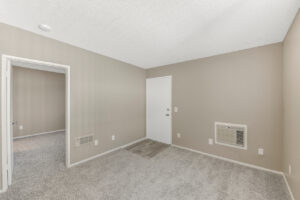 Interior Unit Living Room, Neutral toned Wall paint and Carpeting, in-wall ac unit.