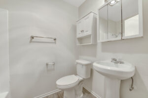 Interior Unit Bathroom, wood like floors, white appliances, white cabinetry.